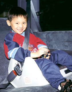 Photo of a happy boy sitting in a child safety seat